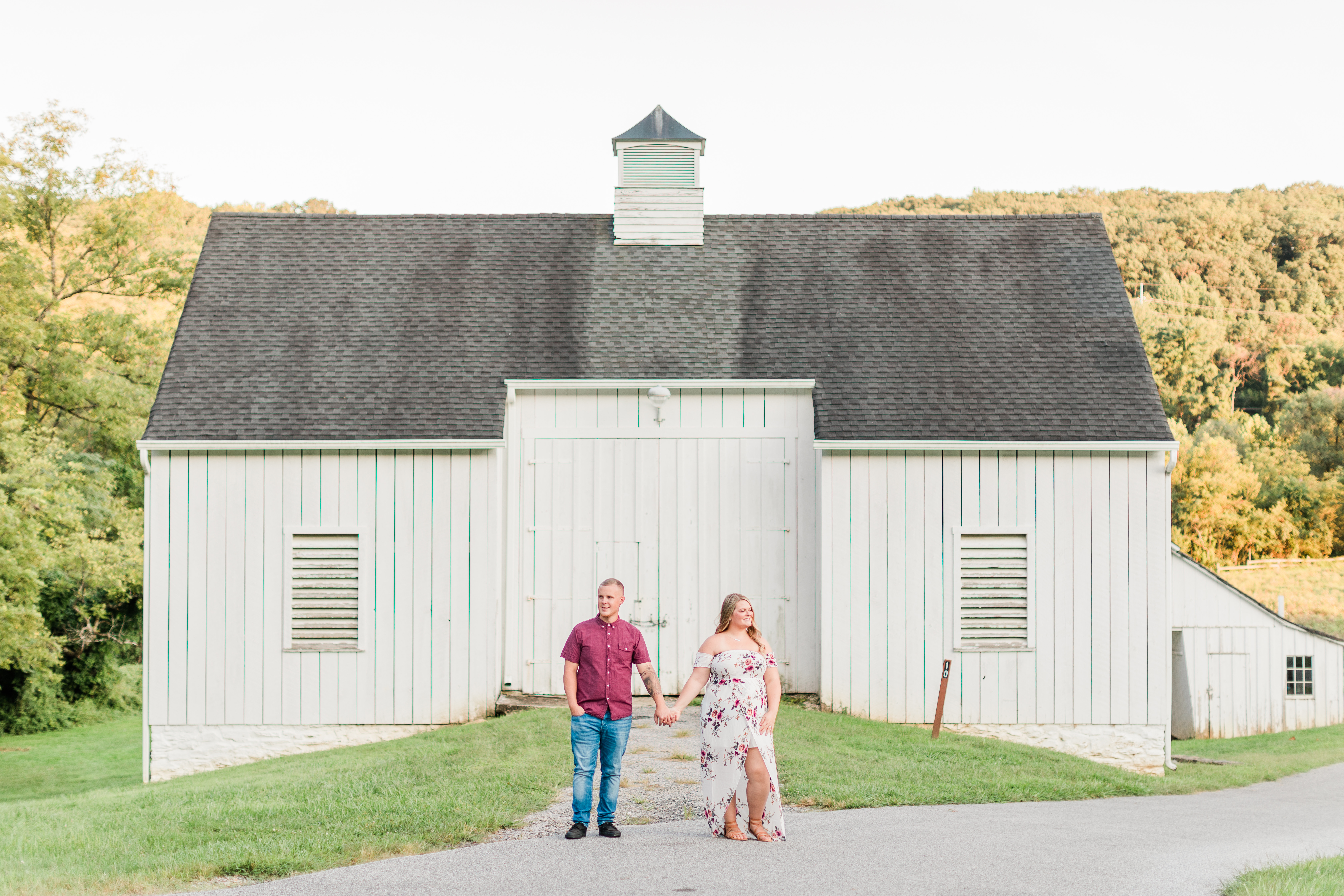A couple stand, holding hands in front of Cromwell Valley Park's barn
