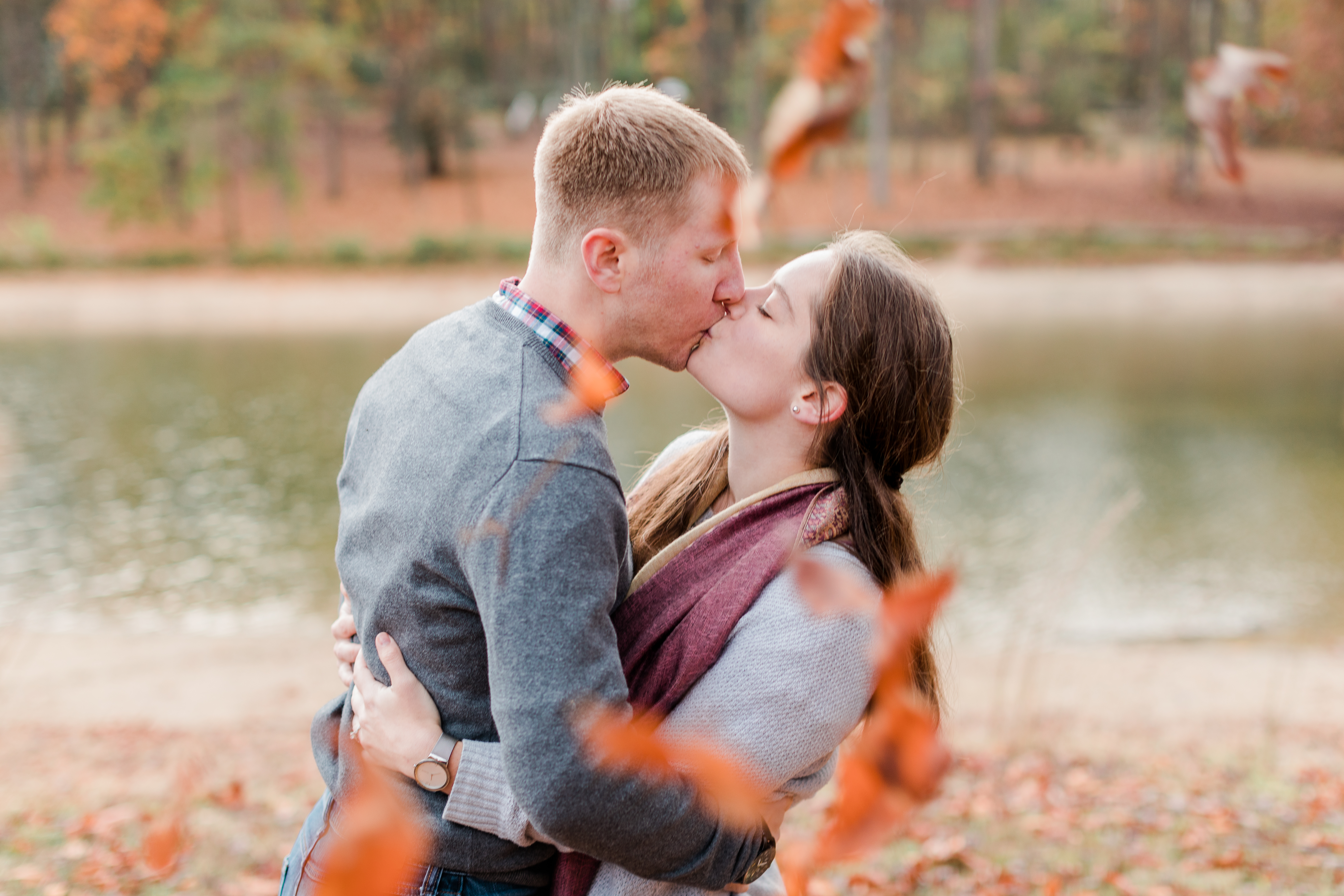 A couple kiss as fall leaves swirl around