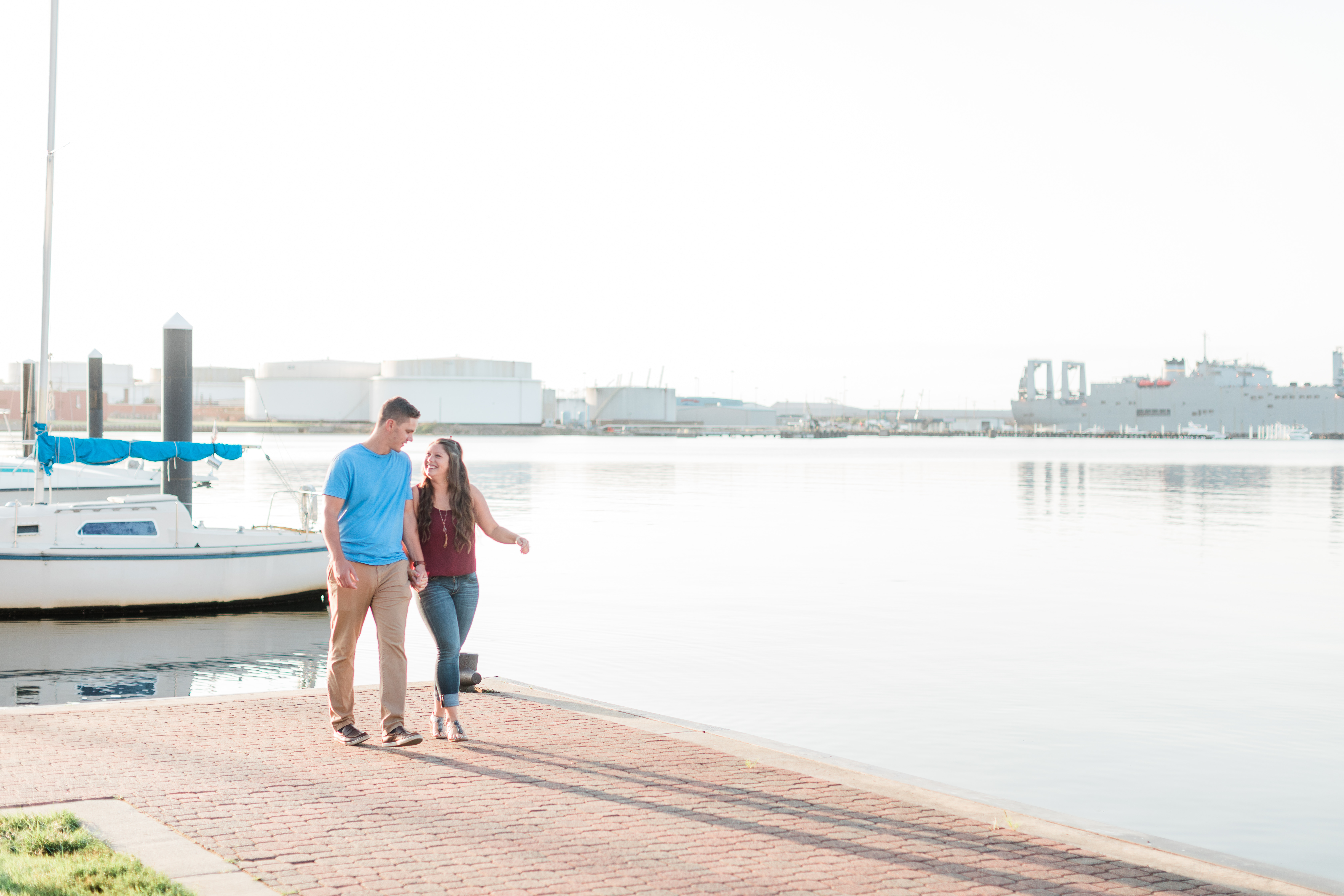 A cute couple walk playfully together on the dock of the Baltimore Canton waterfront