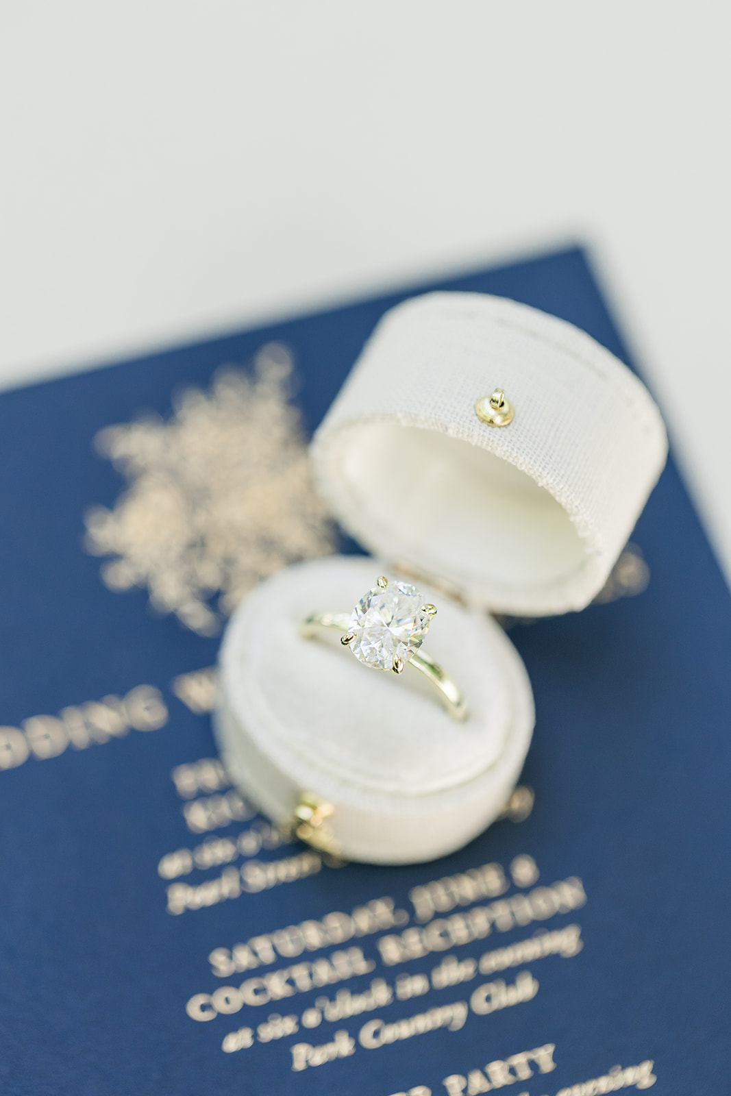 Large engagement ring in a white heirloom box on blue stationary during an Annapolis Maryland wedding