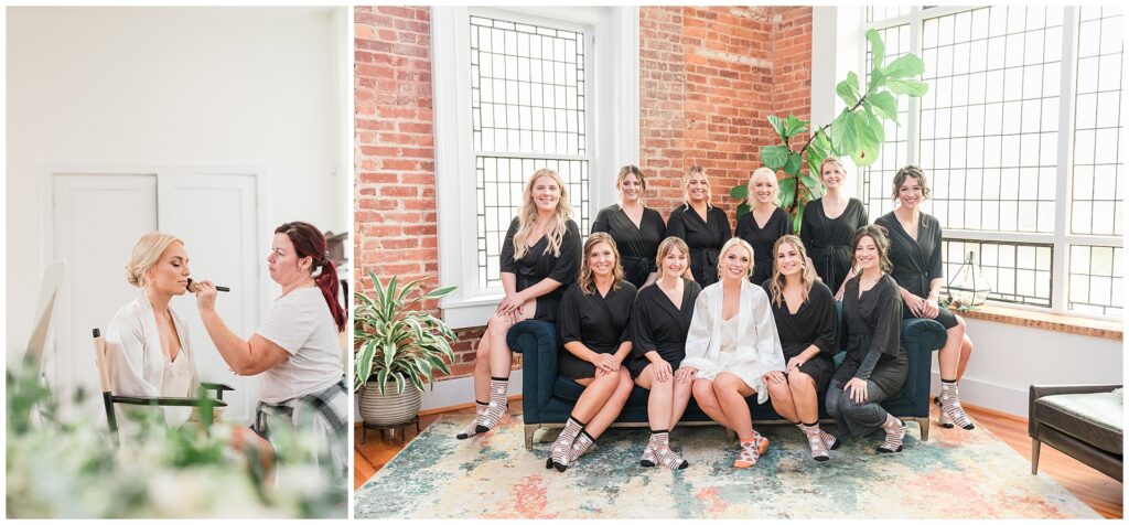 Bridesmaids in matching black robes with bride in white, historic brick venue with modern furnishings