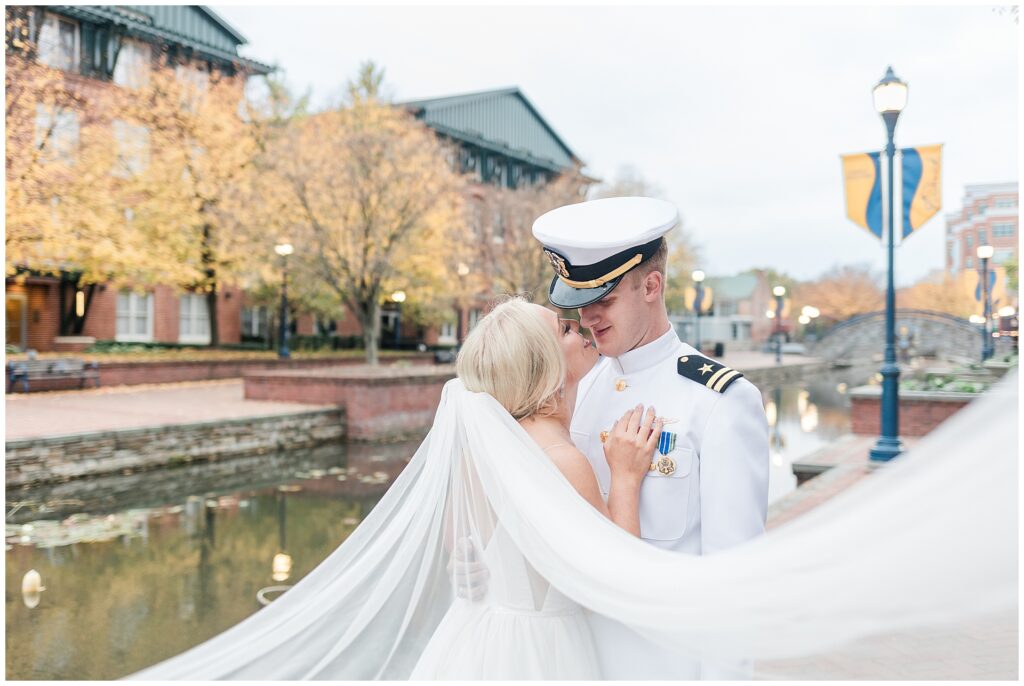 Navy officer and bride portrait along Carroll Creek with dramatic veil and fall colors in downtown Frederick