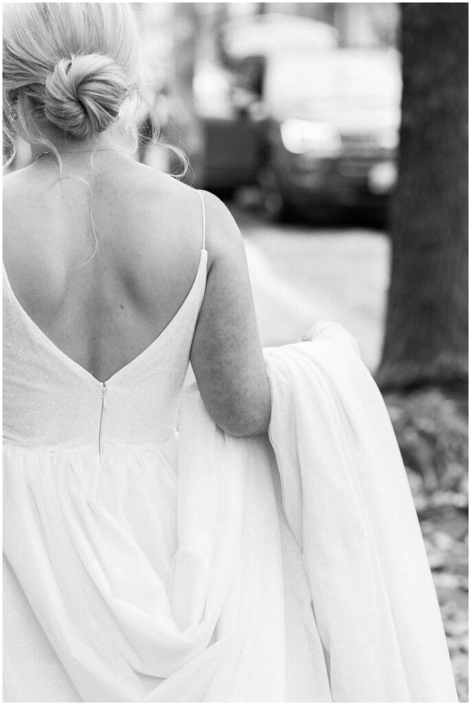 Black and white fine art portrait of bride's classic v-back wedding gown with elegant updo, timeless bridal style