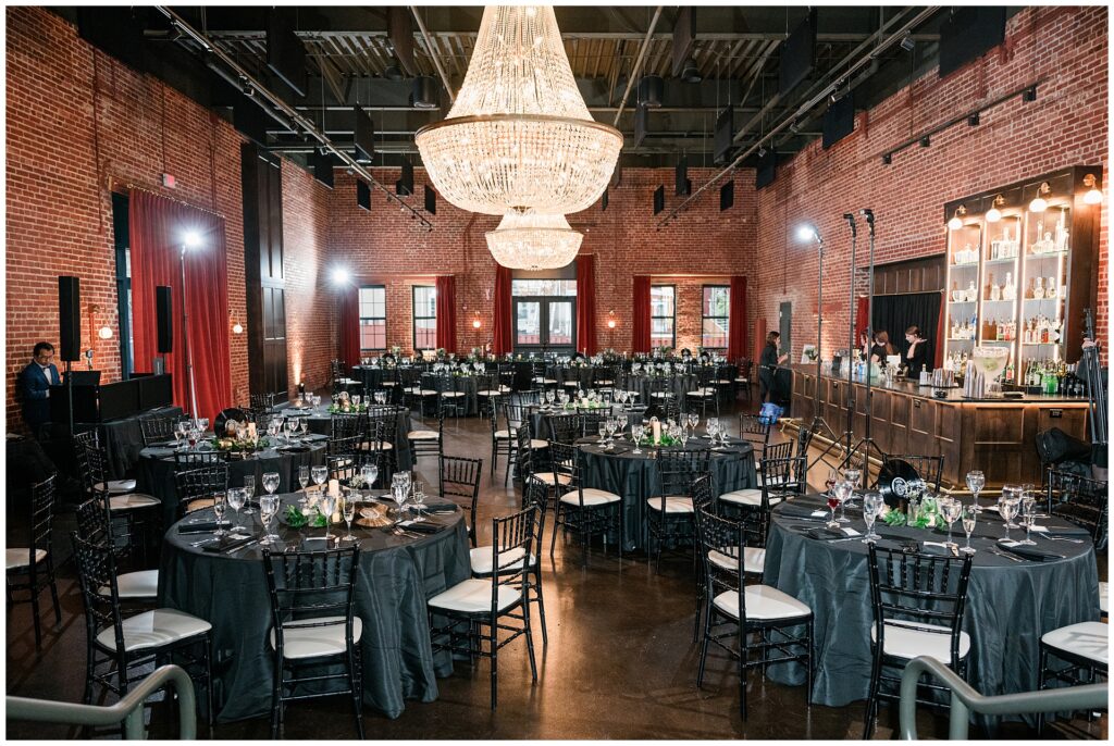 Elegant wedding reception at Union Mills Public House featuring crystal chandeliers, exposed brick walls, and black tie decor with navy wedding details in downtown Frederick