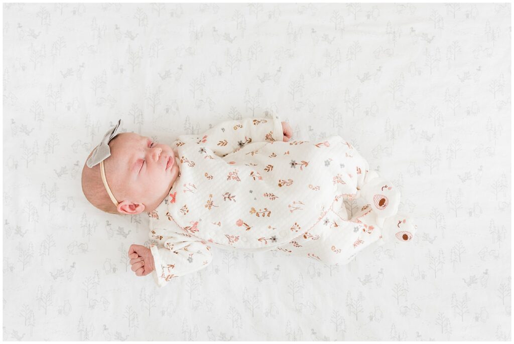 A newborn baby girl in a soft floral print on her textured bedsheets during her Maryland Newborn session