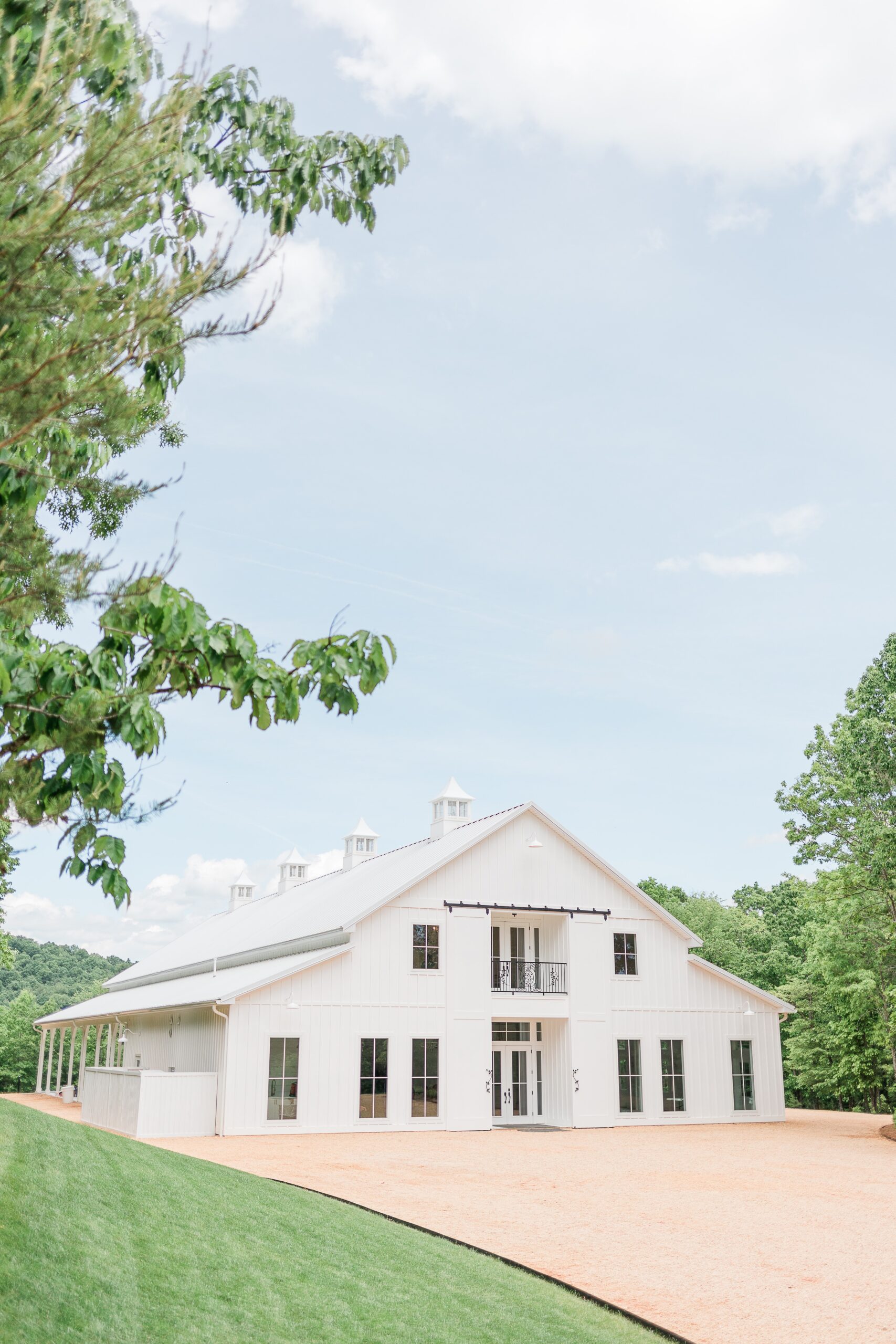 Front exterior view of Ivy Rose Barn surrounded by trees and blue sky