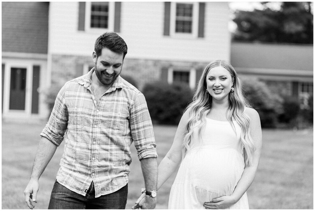 Mom and dad laugh together during their front yard maternity session in Gaithersburg, MD, photographed by a Maryland maternity photographer.