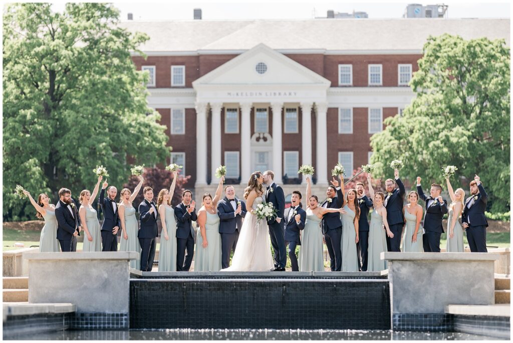 Full wedding party cheering around the ODK Fountain on McKeldin Mall at the University of Maryland, captured during extended timeline photography coverage