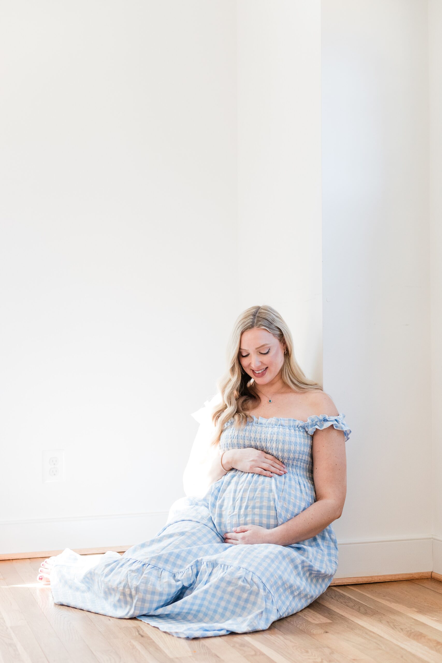 Mother expecting baby boy, in a blue dress, photographed during an in-home maternity session Montgomery County, Maryland.
