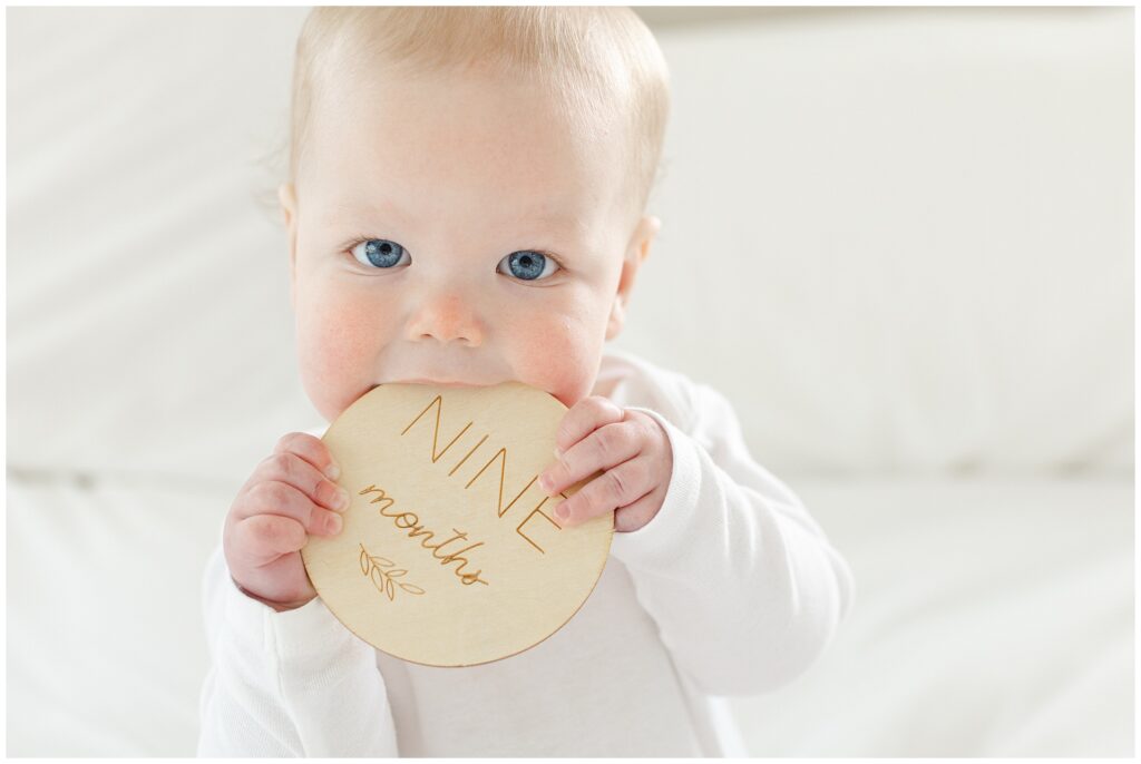 Nine-month milestone photo of baby with minimal styling and natural window light in Maryland