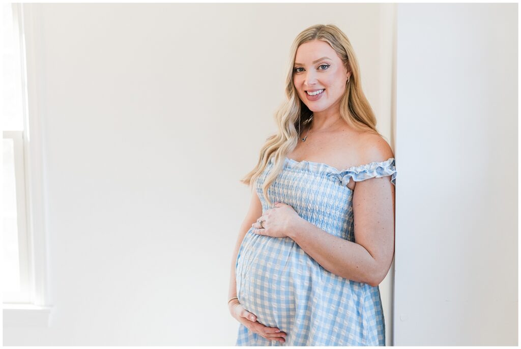 Pregnant mother in a blue gingham maternity dress during an in-home photo session