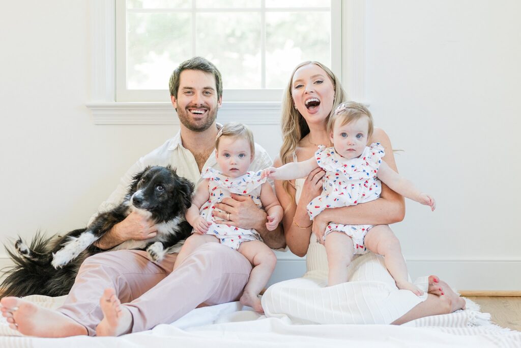 Parents sitting with their one-year-old twin daughters during an in-home family session in Montgomery County, Maryland.