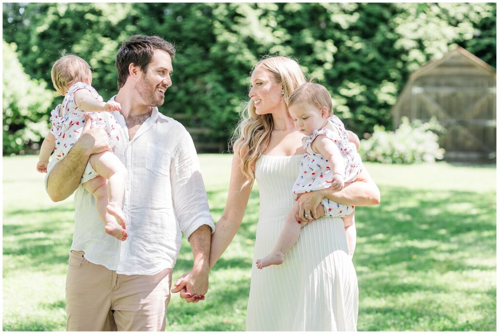 Parents walking with their one-year-old twin girls during a milestone family session in Gaithersburg, Maryland.