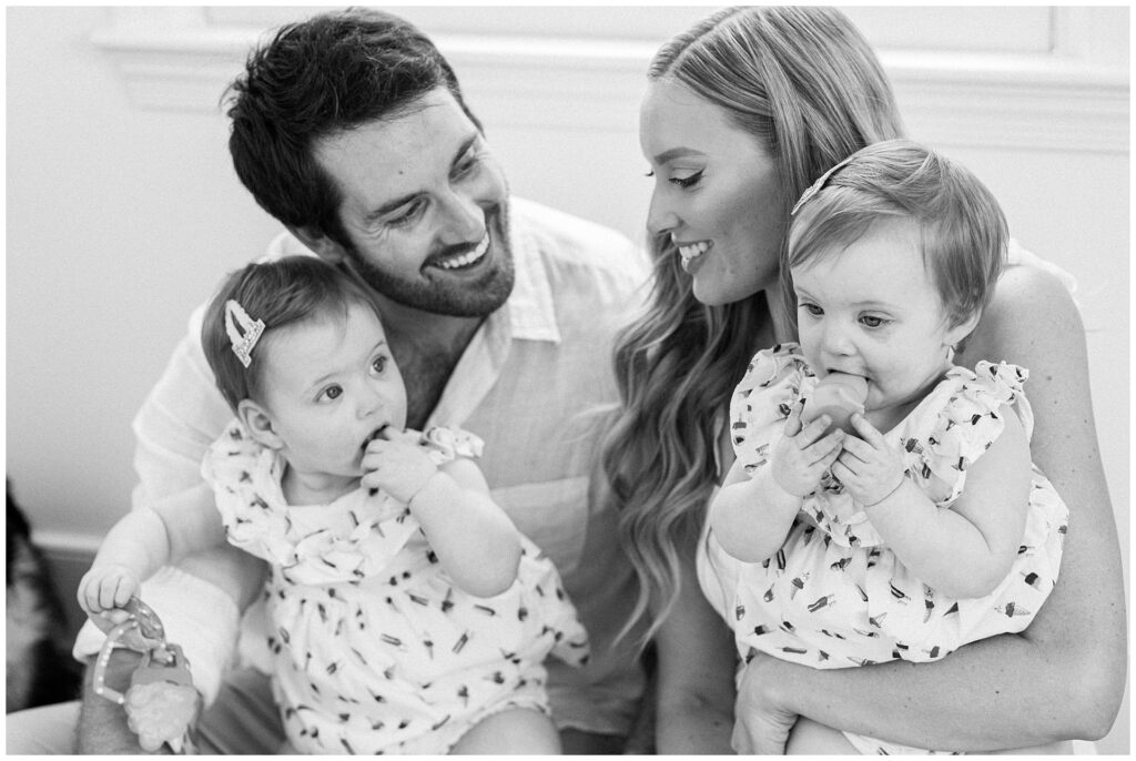 Parents sitting with their one-year-old twin daughters during an in-home family session in Montgomery County, Maryland.