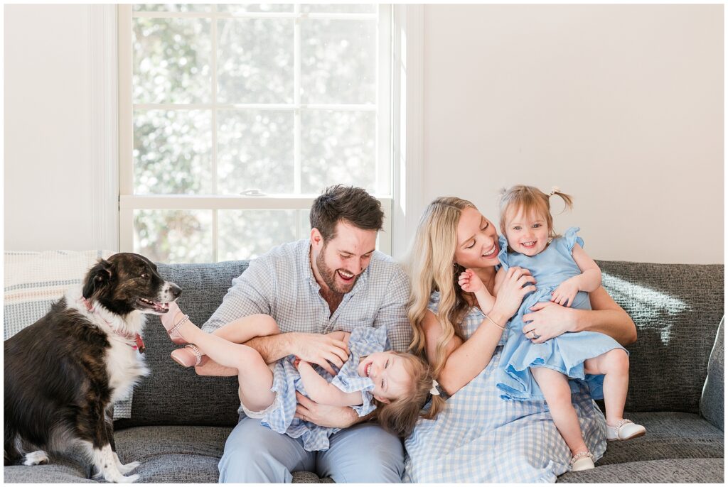 Parents with their twin toddler daughters during an in-home maternity session in Montgomery County, Maryland, celebrating the upcoming arrival of their baby boy.