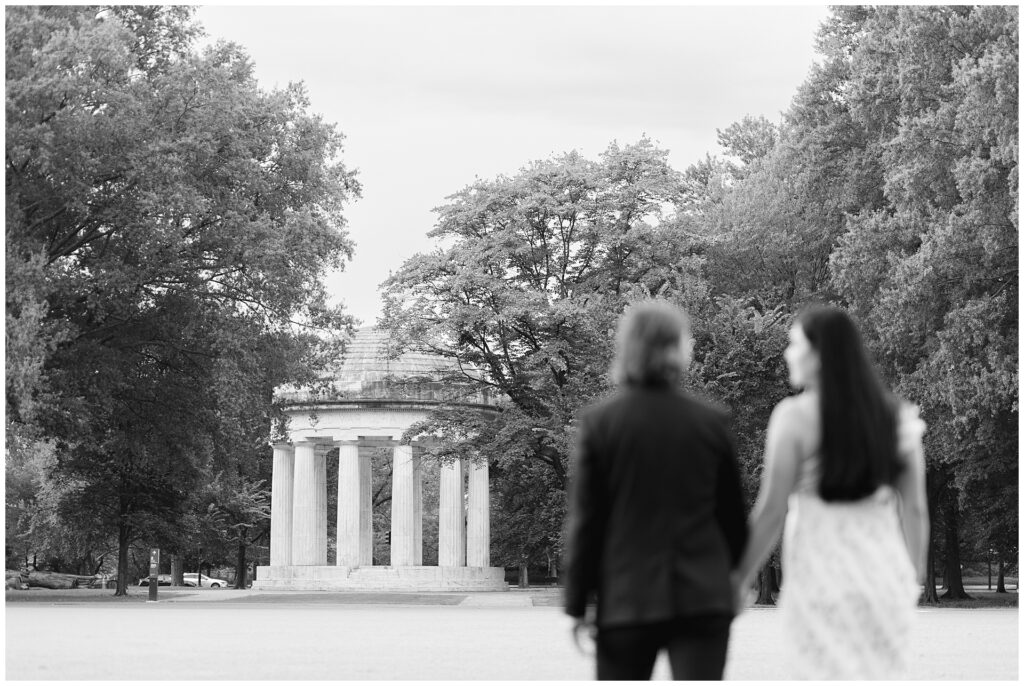 Couple walking hand in hand toward the Ash Wood War Memorial, part of a sunrise session itinerary between the Lincoln and Jefferson Memorials.