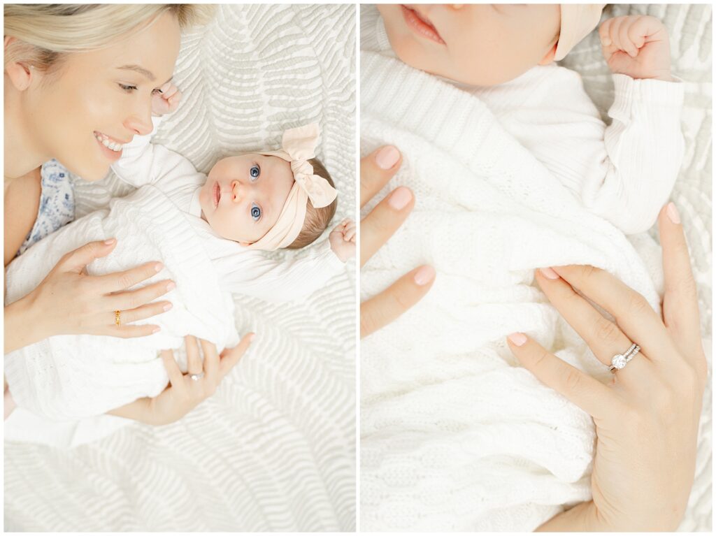 Mom in a white and blue floral dress  holds her baby girl in their newborn home session, in Virginia. She is laying on the bed as the baby looks up at the camera