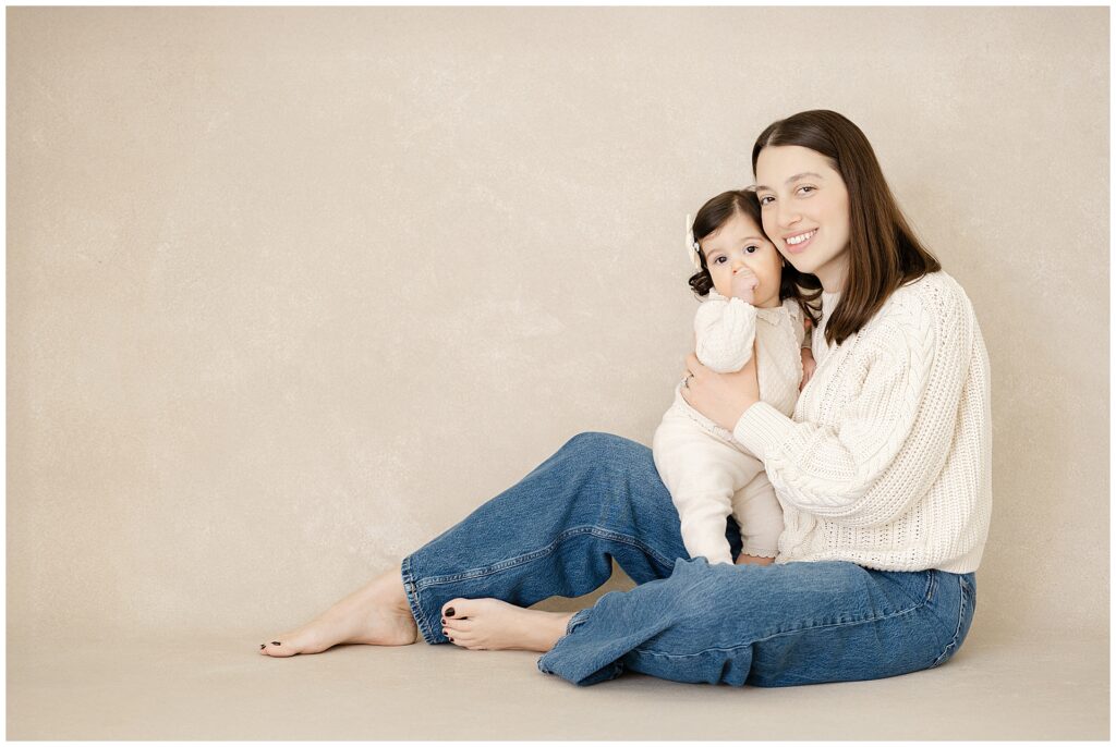 Heirloom-style first birthday portrait of a one-year-old girl and her mother against a hand-painted backdrop during first birthday photos in Annapolis