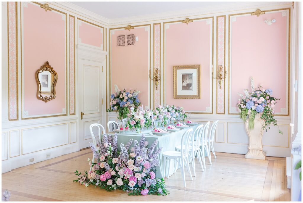 Full view of the pink Music Room at Cairnwood Estate in Bryn Athyn, Pennsylvania, styled for a baby or bridal shower with vibrant pink and purple florals, highlighting an elegant Philadelphia baby shower or Philadelphia bridal shower location inside a historic estate wedding venue near Philadelphia.