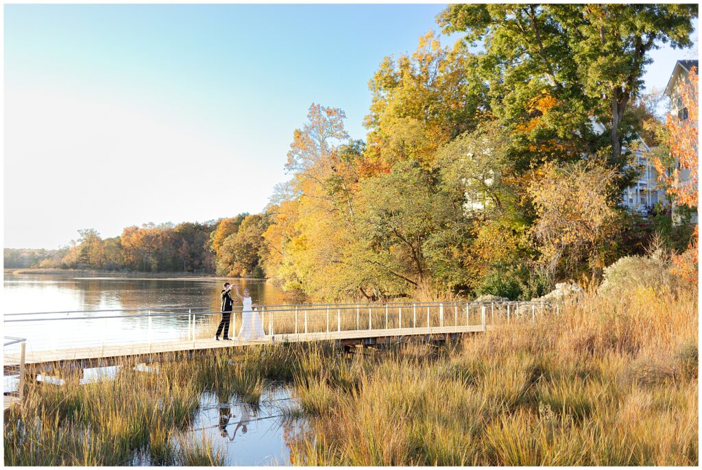 A bride and groom dance on a bridge overlooking the Potomac river on a stunning all day during their maryland waterfront wedding