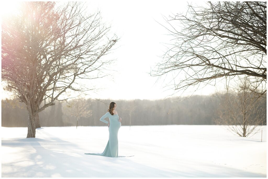 Woman in a green dress during her snow maternity session in Howard County