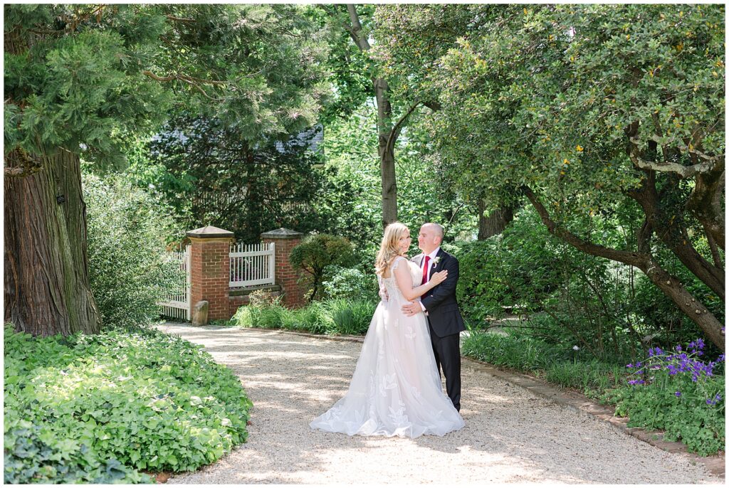 Bride and groom pose on the gravel path in the gardens at the Tudor Palace in Georgetown