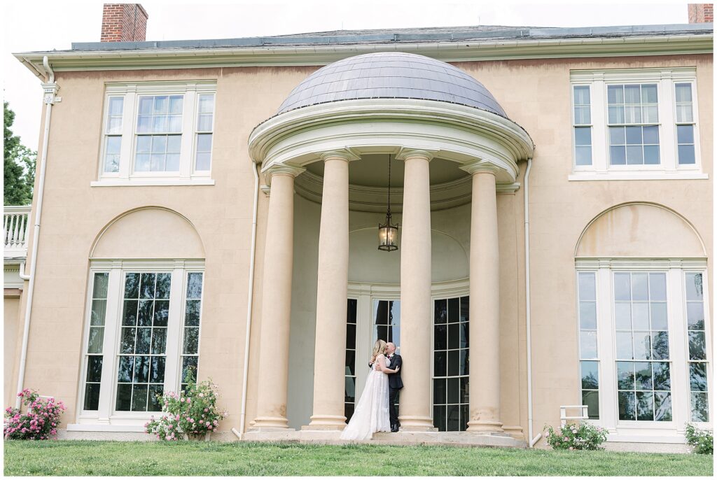 Bride and groom kiss under the domed portico at the Tudor Place Manor in Georgetown